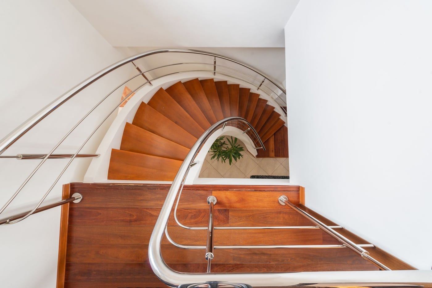 Curved hardwood staircase with polished steel handrails